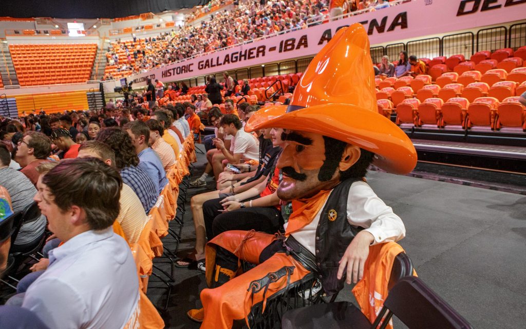 Pistol Pete sitting with a crowd of students in Gallagher-Iba Arena