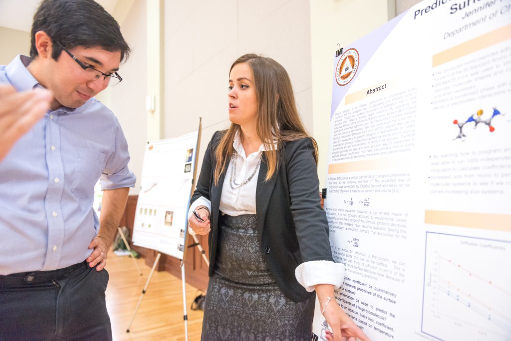A woman uses a poster presentation aid at a research conference.