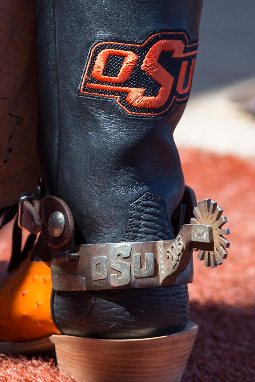 A black boot with spurs with an OSU logo on the calf of the boot