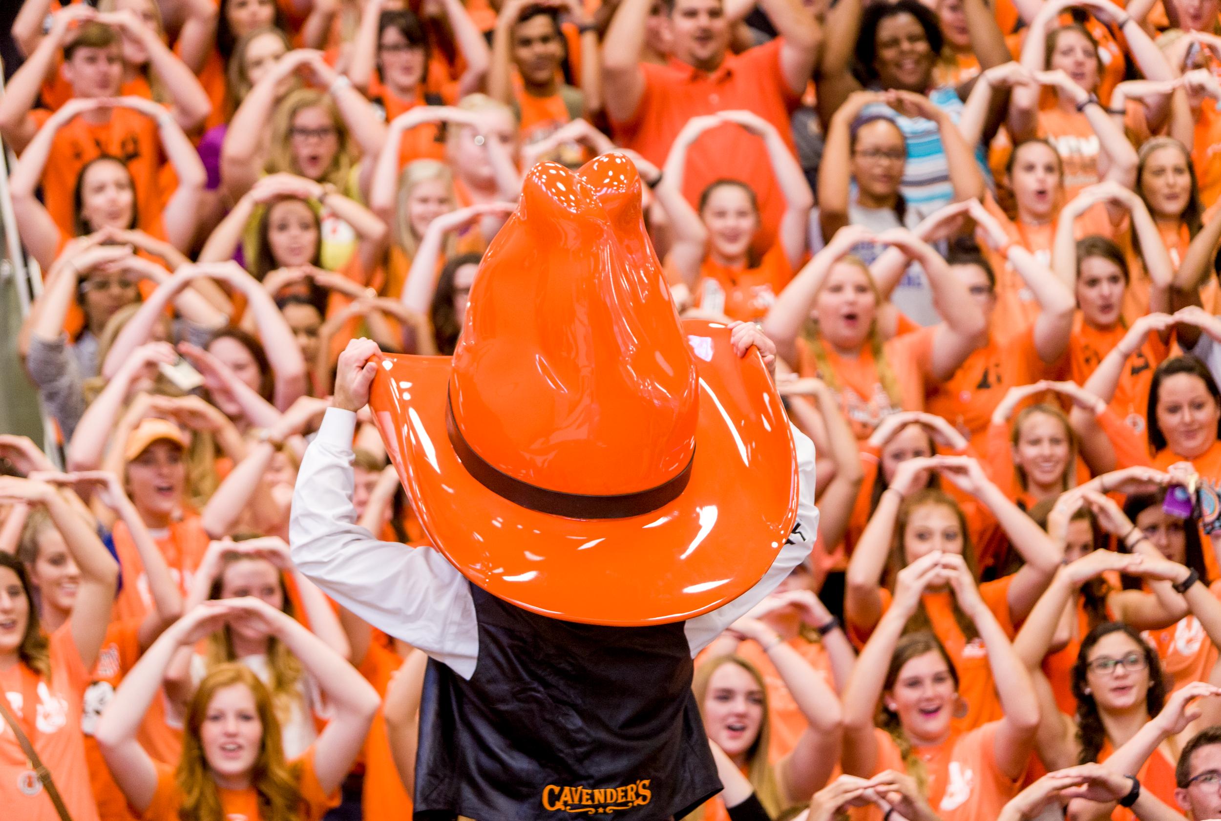 Pistol Pete stands in front of a sea of fans dressed in orange while leading them in the O-S-U chant.