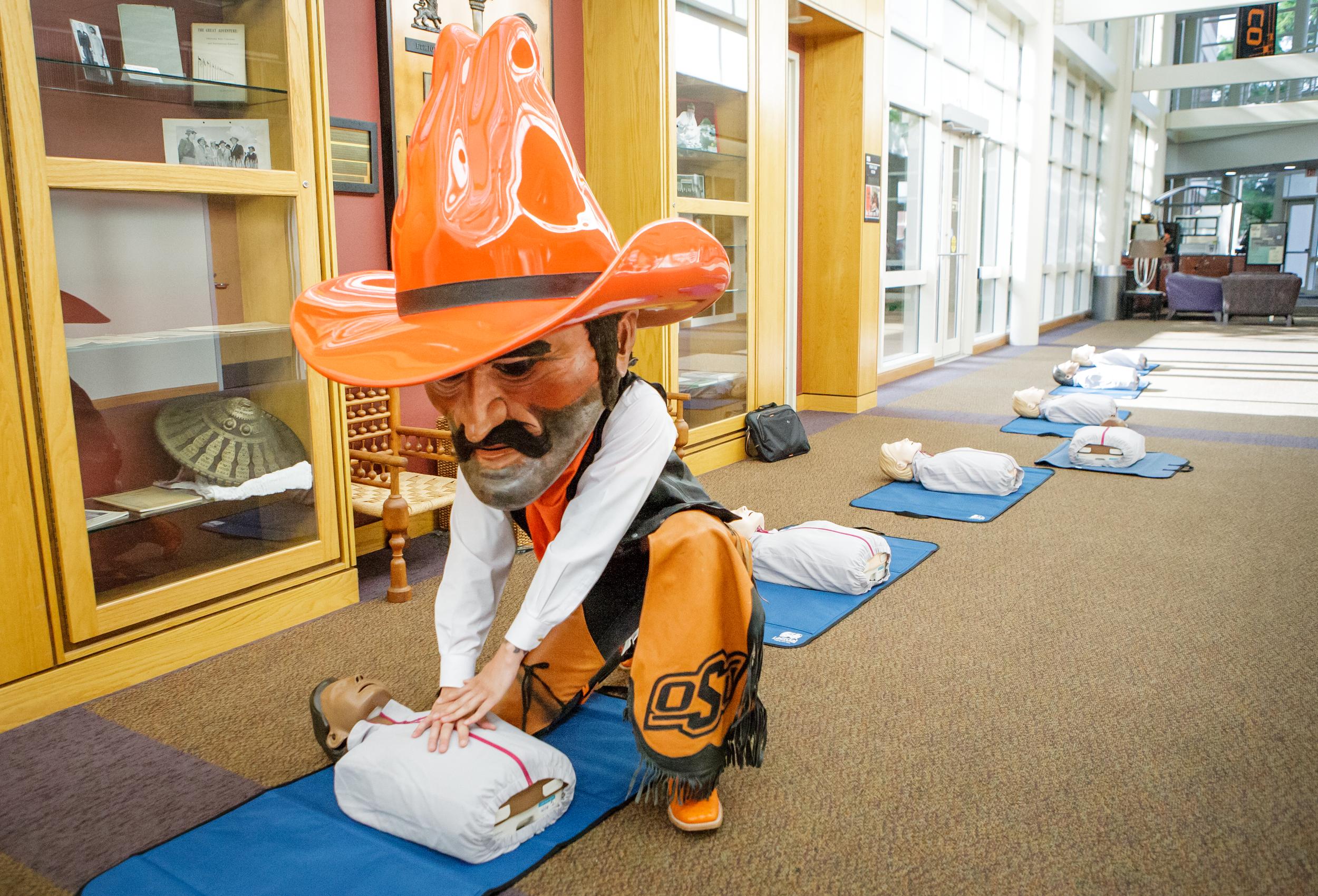 Pistol Pete demonstrates how to perform CPR using a dummy on the ground