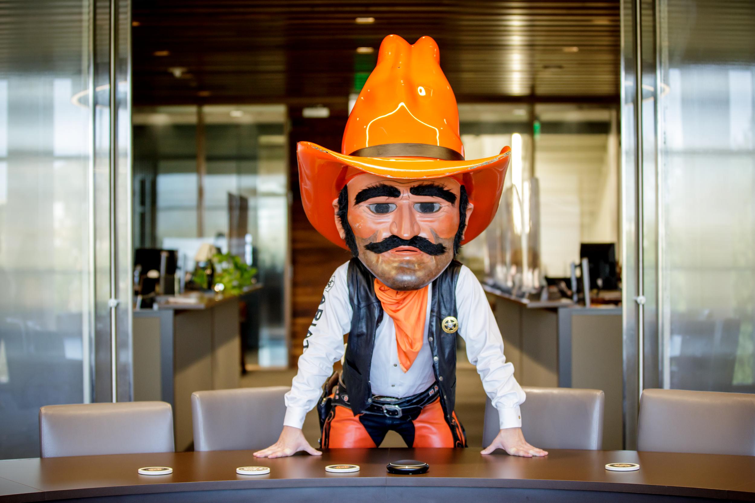 Pistol Pete demonstrates a power pose in a boardroom in the Spears College of Business.