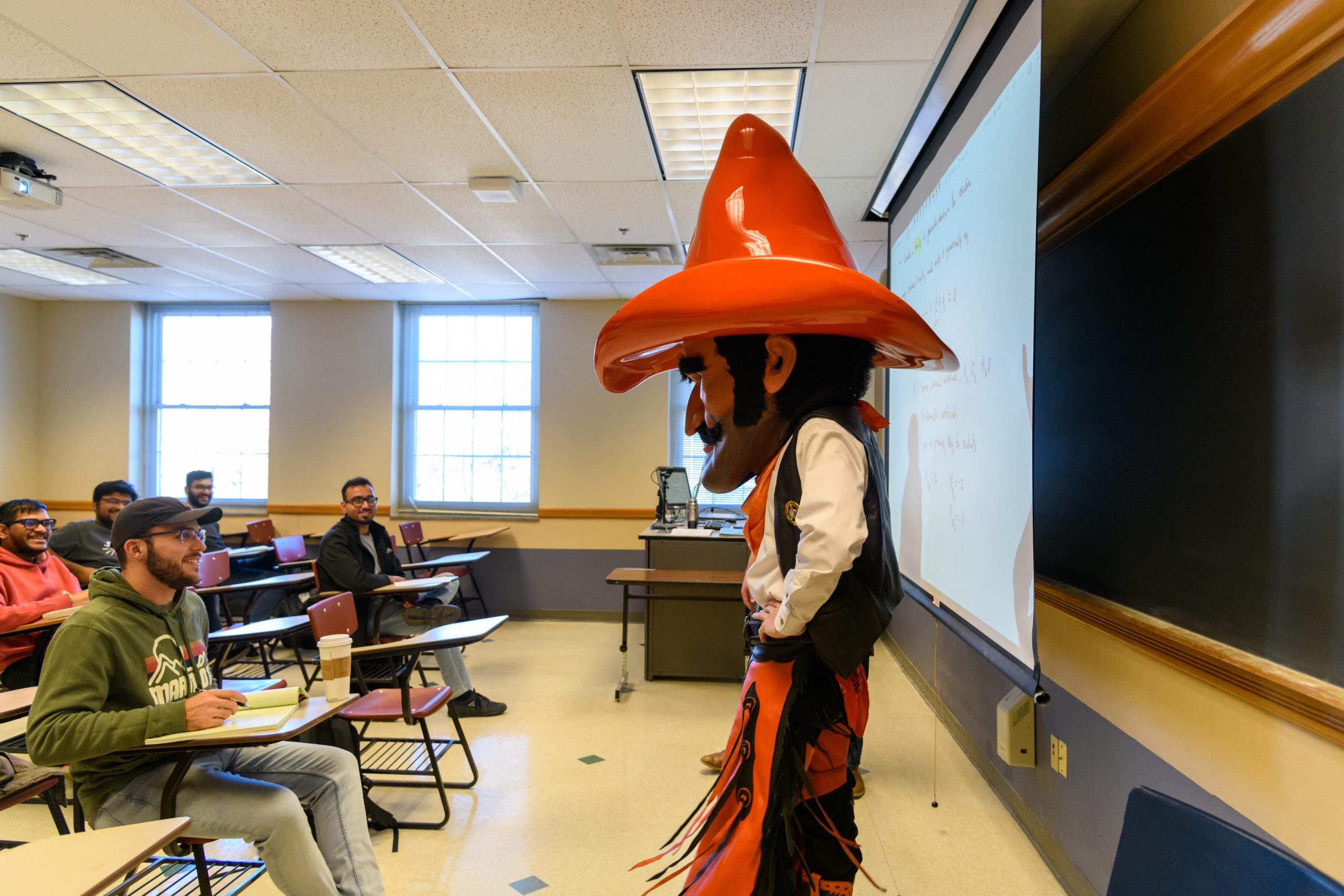 Pistol Pete lecturing in front of a classroom of students with his notes on the projector screen.