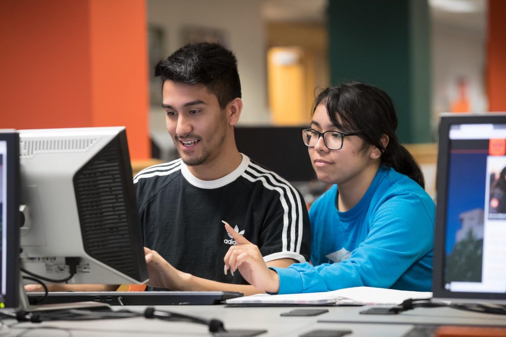 Two students sitting at a library computer desk