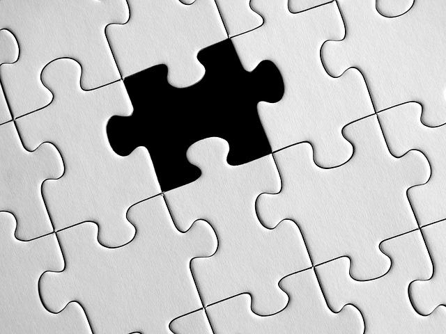 A close-up shot puzzle consisting of all white pieces, with one piece missing.