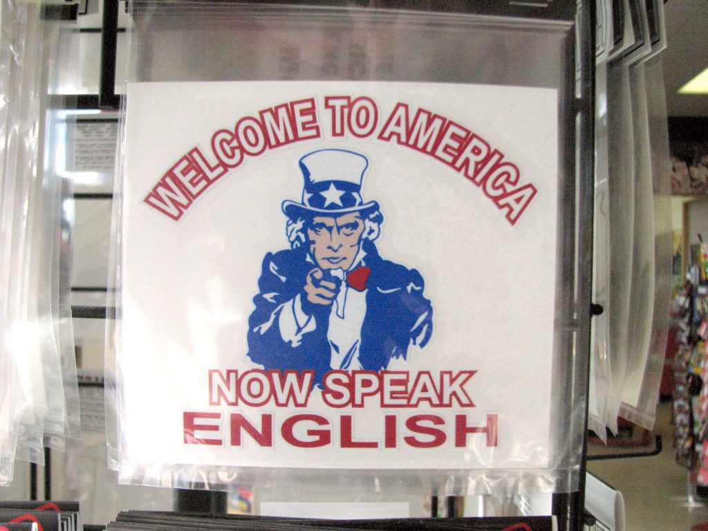 A sign that says "Welcome to America. Now speak English." with a blue-and-white image of Uncle Sam pointing at the viewer.