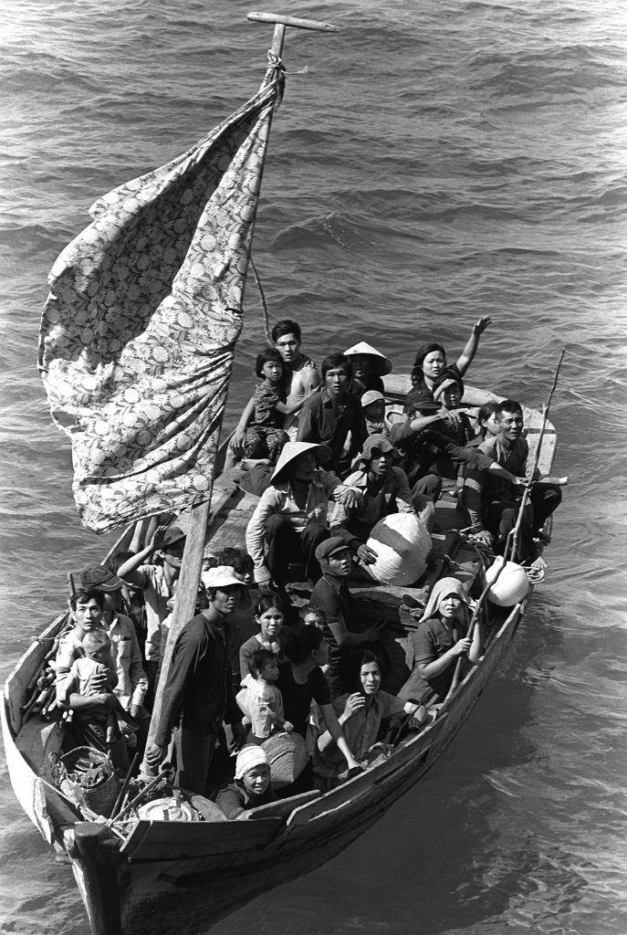 A black and white photo of roughly 35 refugees from Vietnam in a small boat