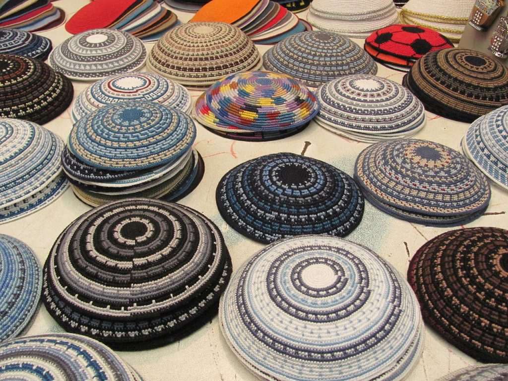 Dozens of handmade yarmulkes on a table.