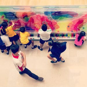 School children playing with the Art Corridor, a moveable artwork which transmutes in color as players shift elements around the work.