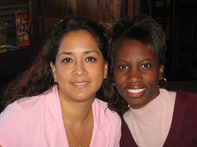 Two women side by side, one with light brown skin and one with dark brown skin.