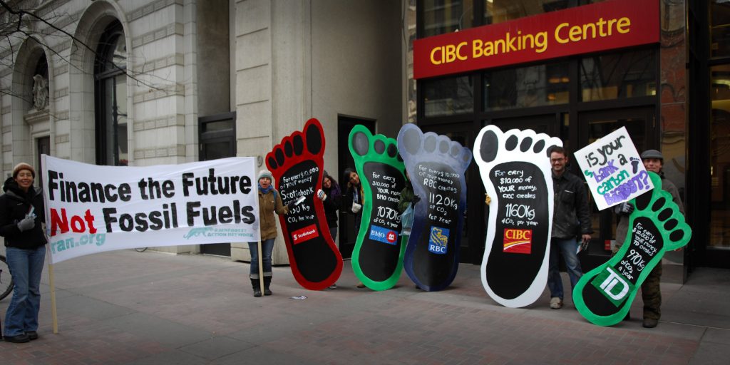 Seven people protesting against fossil fuels on the pavement outside the CIBC Banking Center.